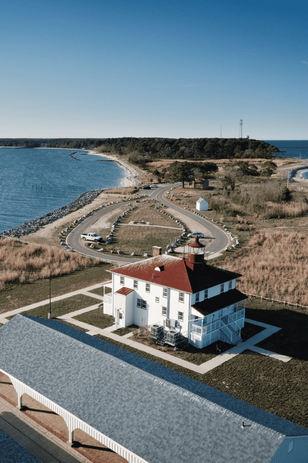 Dockside lighthouse with coastal view and parking area, scenic seaside location, popular for navigation and sightseeing.