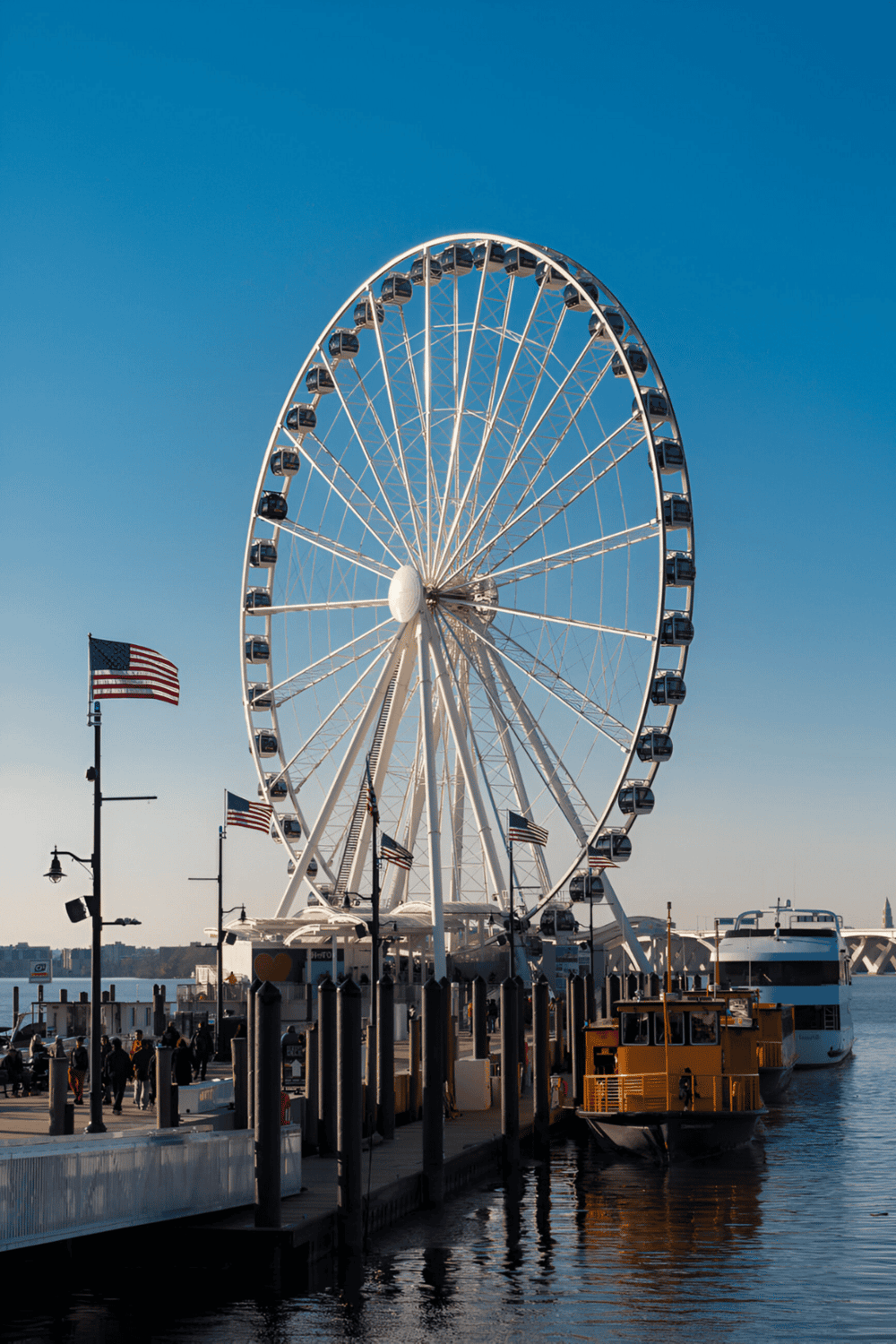 Amusement park Ferris wheel by waterfront, iconic city attraction and scenic view with boats and flags.