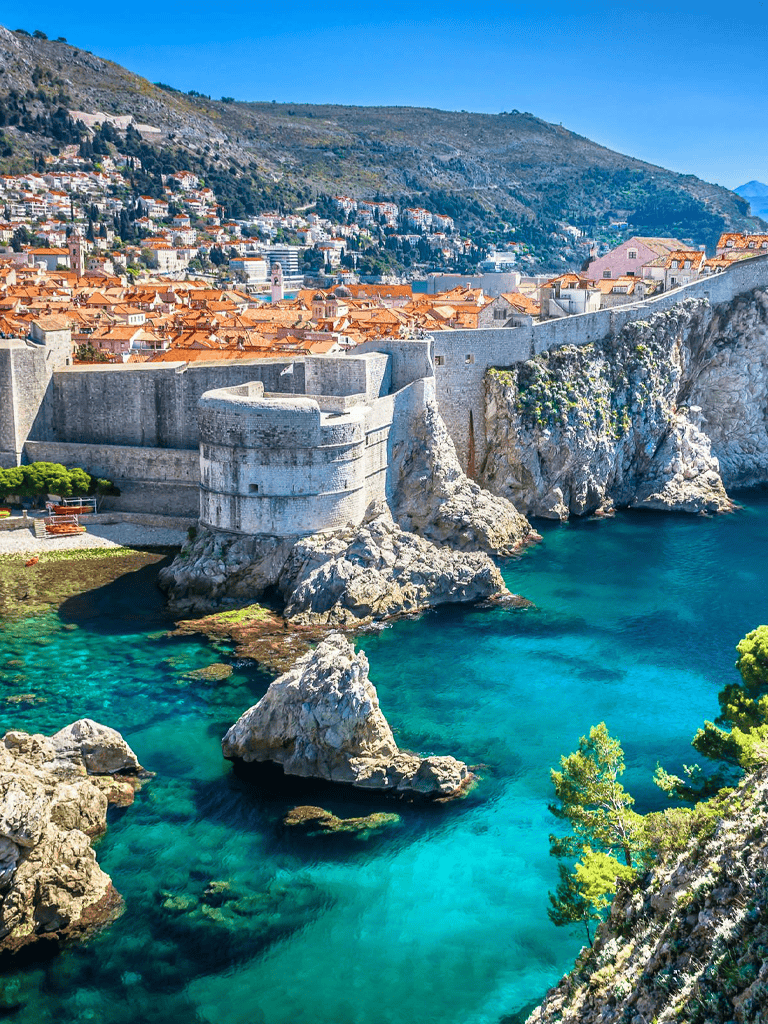 Clifftop Dubrovnik city walls along crystal-clear Adriatic Sea, Croatia, travel destination.