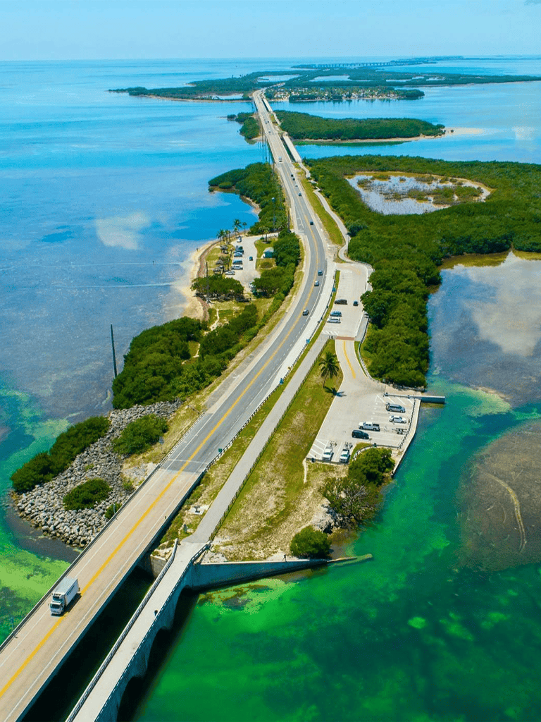 Steel bridge spanning over vibrant green and blue waters, connecting land with scenic coastal views.