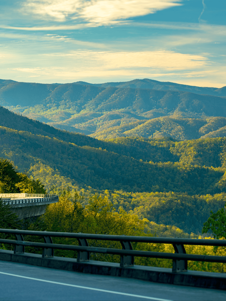 Scenic mountain view with winding highway, lush greenery, and blue sky, perfect for travel and adventure enthusiasts.