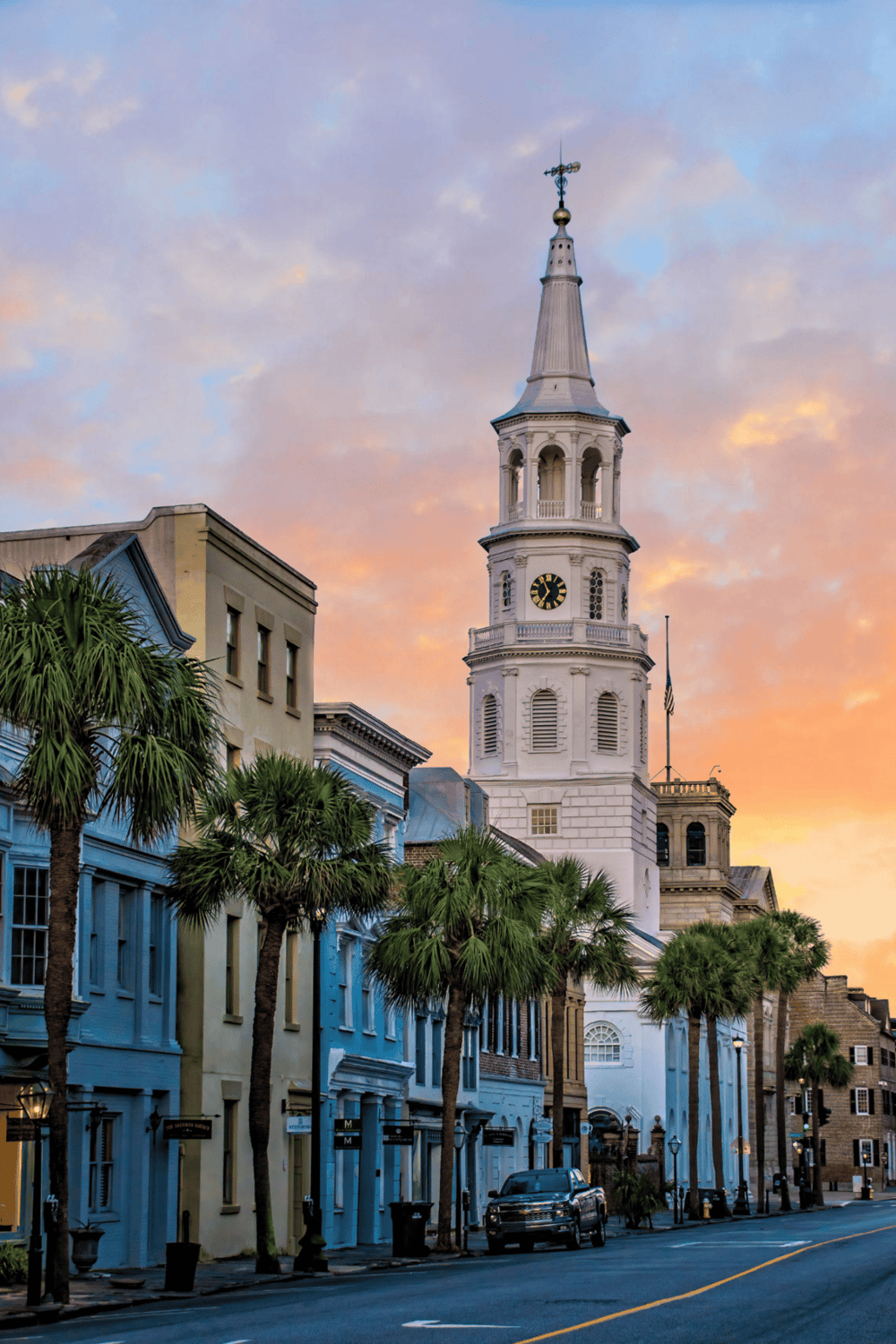Colorful sunset behind Charleston cityscape with historic church steeple and palm trees; perfect for travel and city guide SEO.