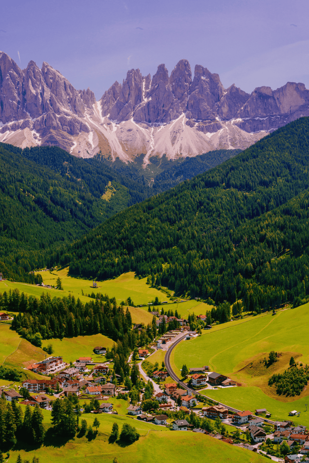Scenic mountain landscape with lush green valley and alpine village in Italy.