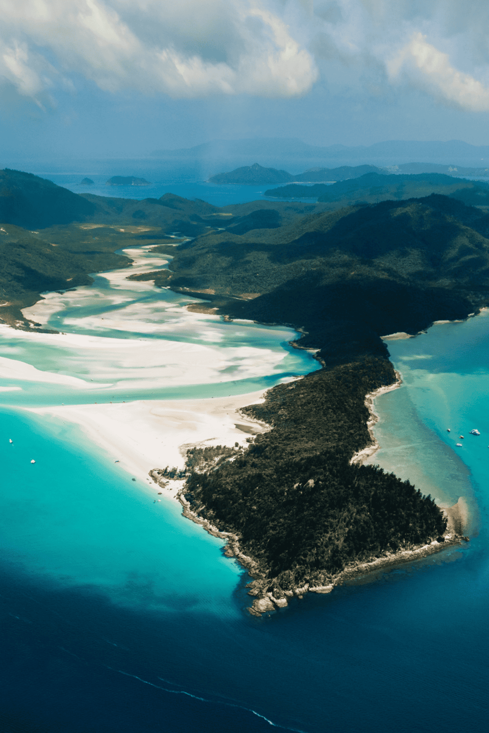 Vibrant aerial view of lush mountains and turquoise coastal waters in a scenic landscape.