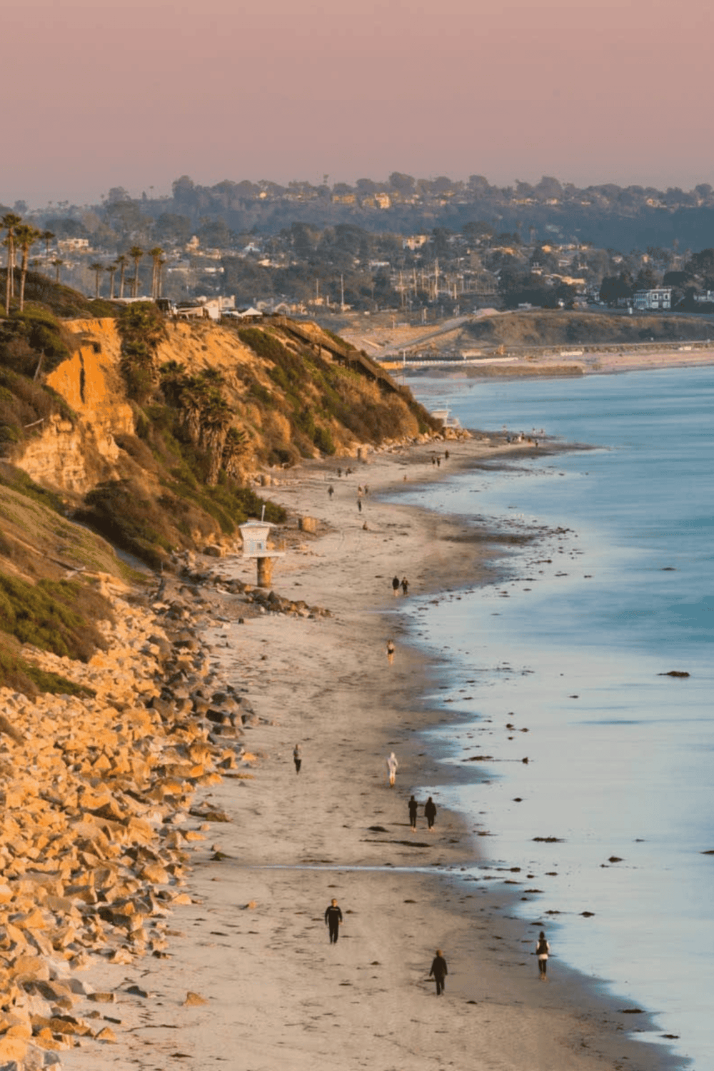 Seaside cliffs and sandy beach along California coast for travel and scenic exploration.