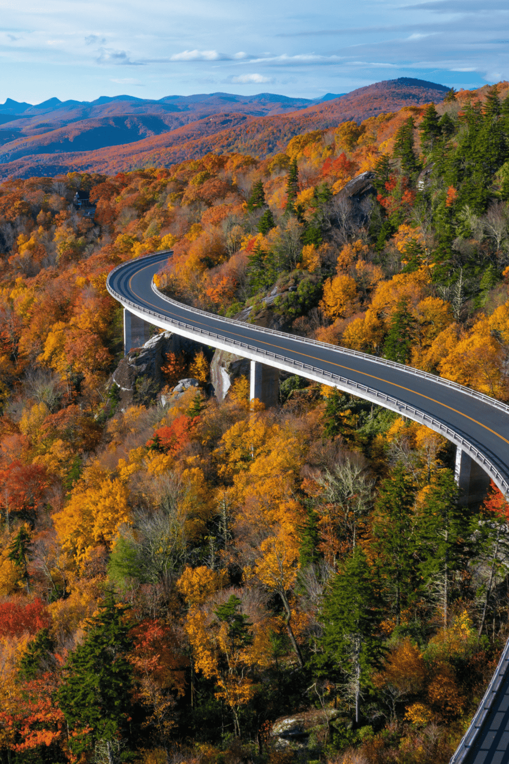 Vivid autumn landscape with winding mountain road through colorful fall foliage in scenic wilderness.