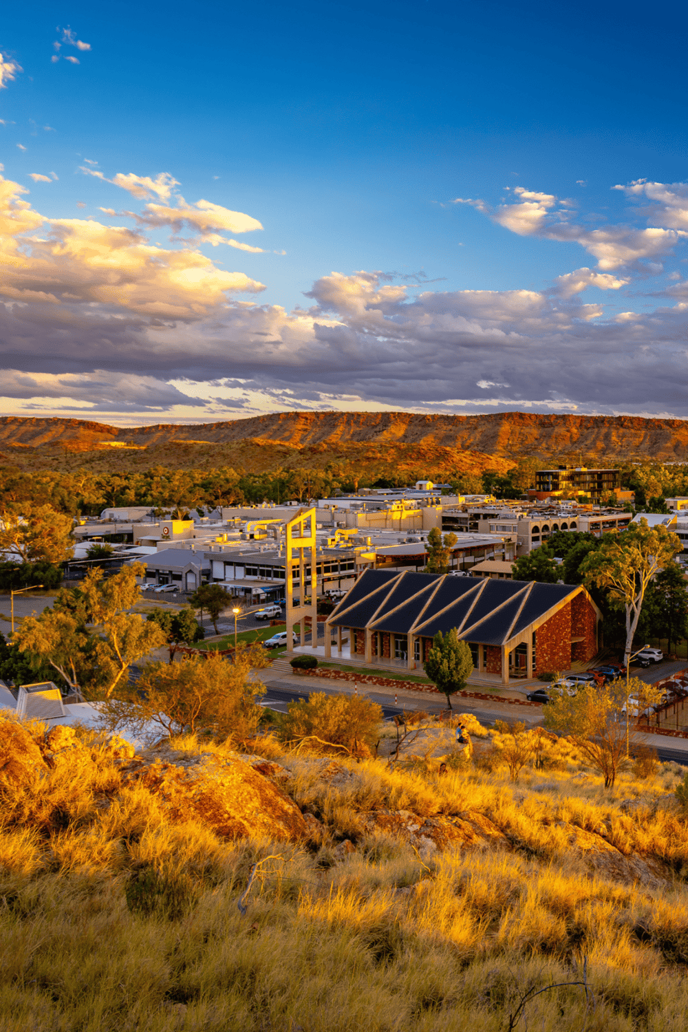Modern shopping center in scenic desert landscape with mountains in the background, during golden hour.