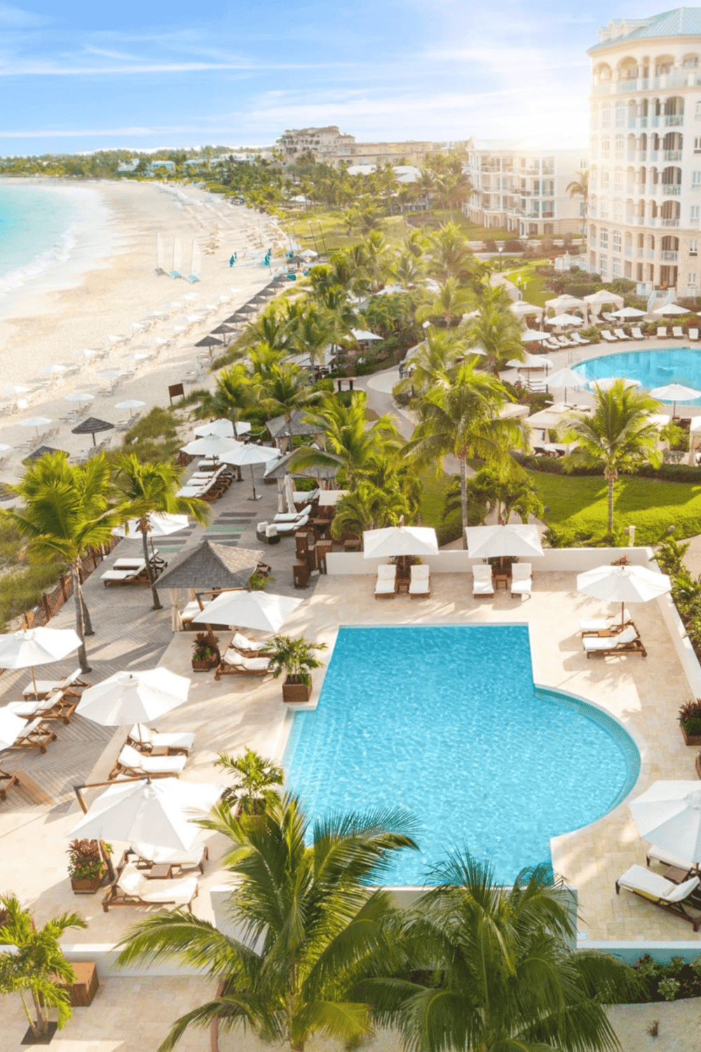 Luxurious beachfront resort with pool, palm trees, and ocean view for perfect tropical vacation.