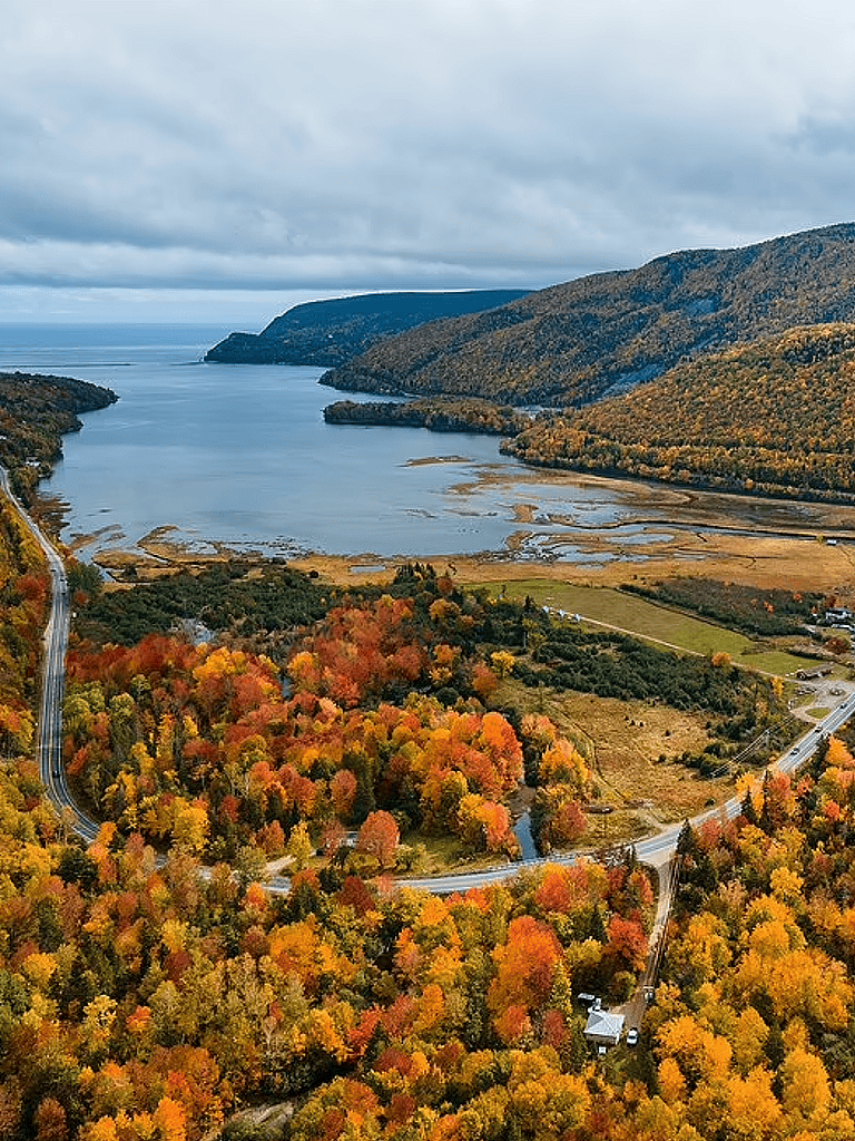 Scenic autumn landscape with colorful fall foliage, winding road, and a river in the background, ideal for travel and outdoor adventure.