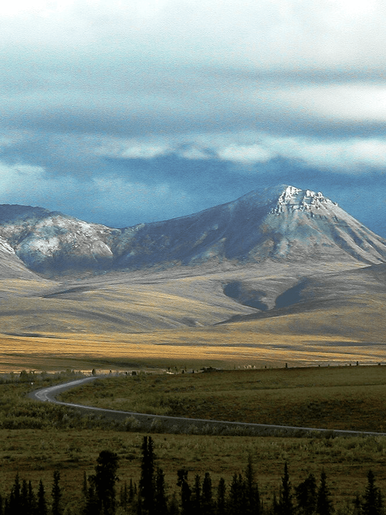 Breathtaking mountain landscape with snow-capped peaks and open plains, ideal for outdoor adventures and scenic drives.