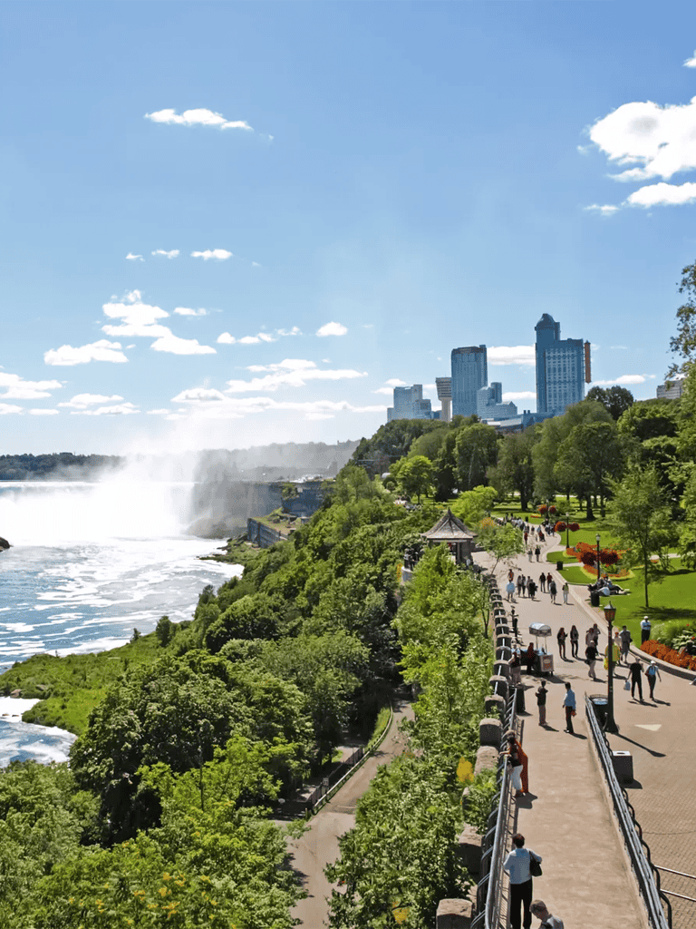 Vibrant cityscape view of Niagara Falls with lush green park and visitors enjoying the scenic outdoor area.