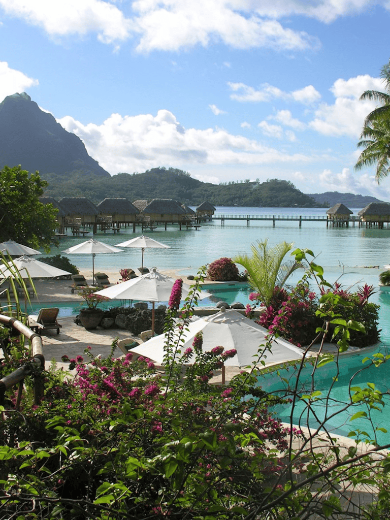 Luxurious tropical resort with overwater bungalows, infinity pool, and scenic mountain views.