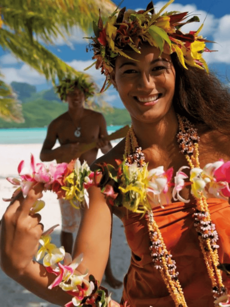 Colorful Hawaiian leis and traditional attire at a tropical beach celebration.