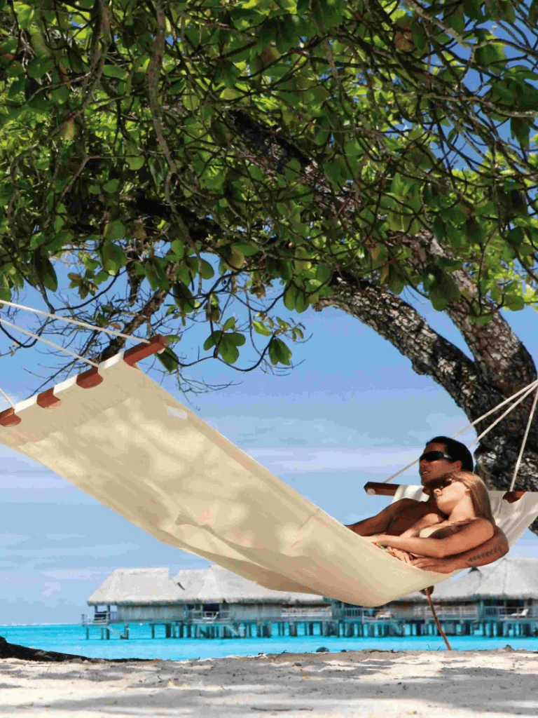 Relaxing couple on hammock under tropical tree over turquoise ocean at overwater bungalow, vacation, paradise, travel, beach, relaxation, Adventure, Dream, travel destination, QuestforDirections.