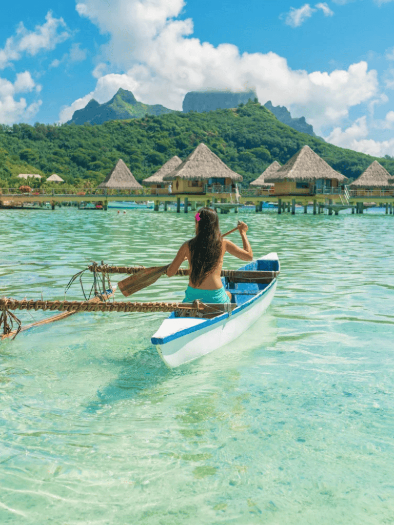 Tranquil tropical island overwater bungalows with a woman in a boat.