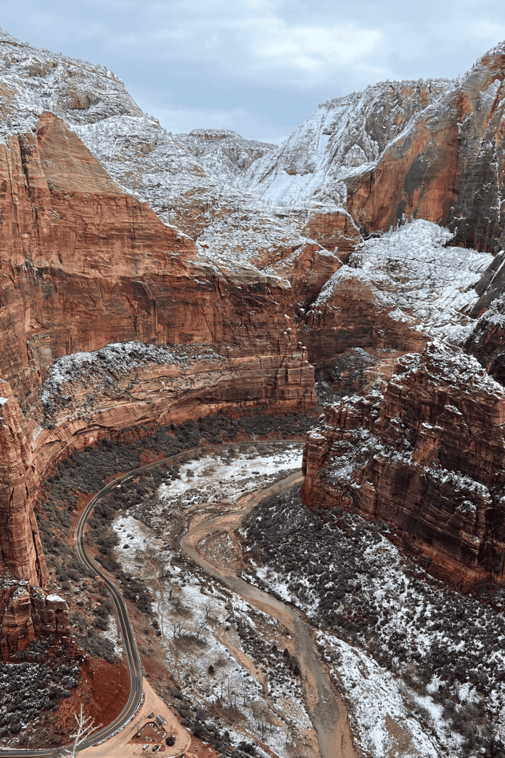 Snow-covered canyon landscape with winding road, scenic views, and red rock formations.