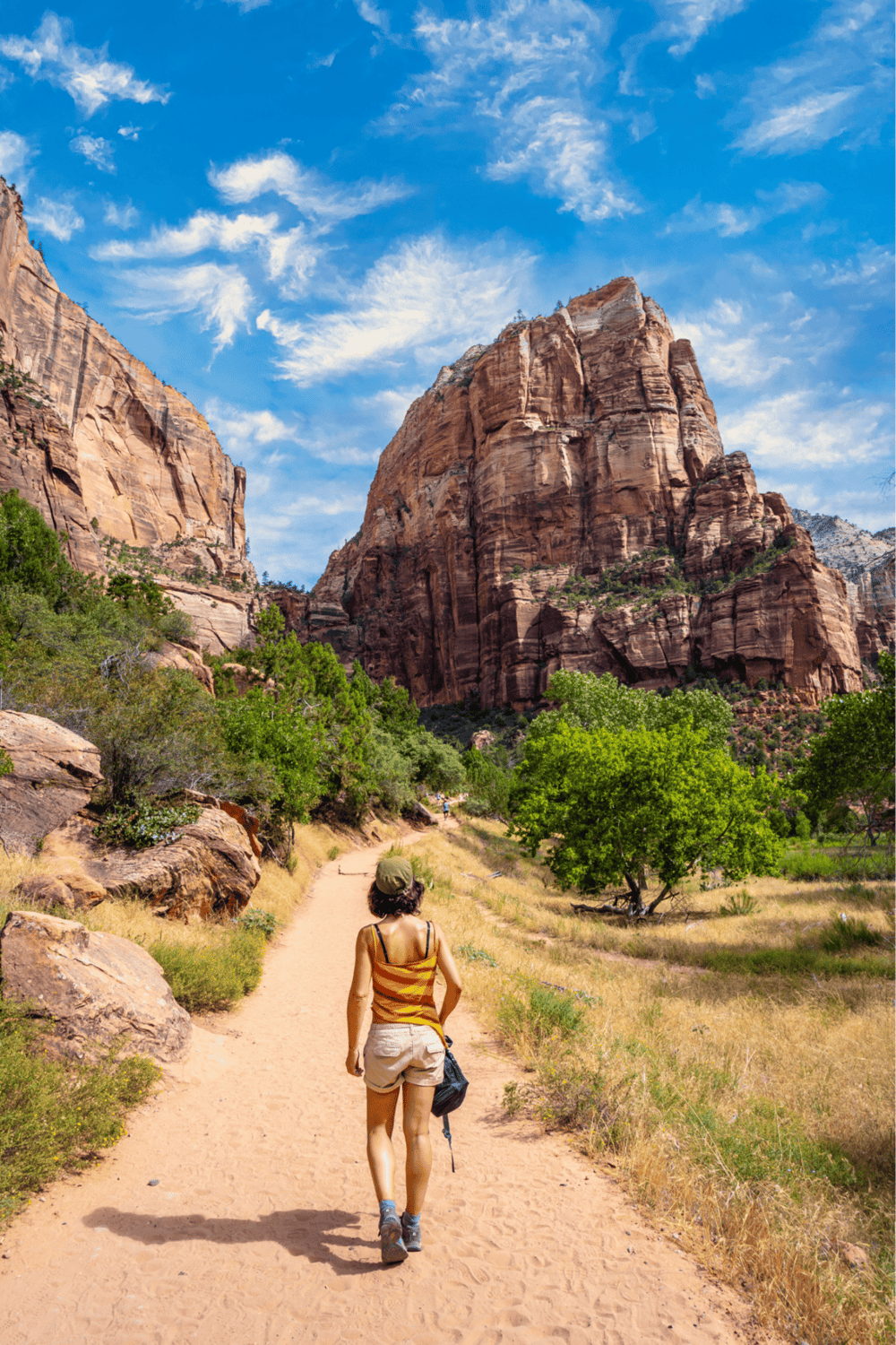 Serene hiking trail in Zion National Park with towering red rock formations and clear blue sky.