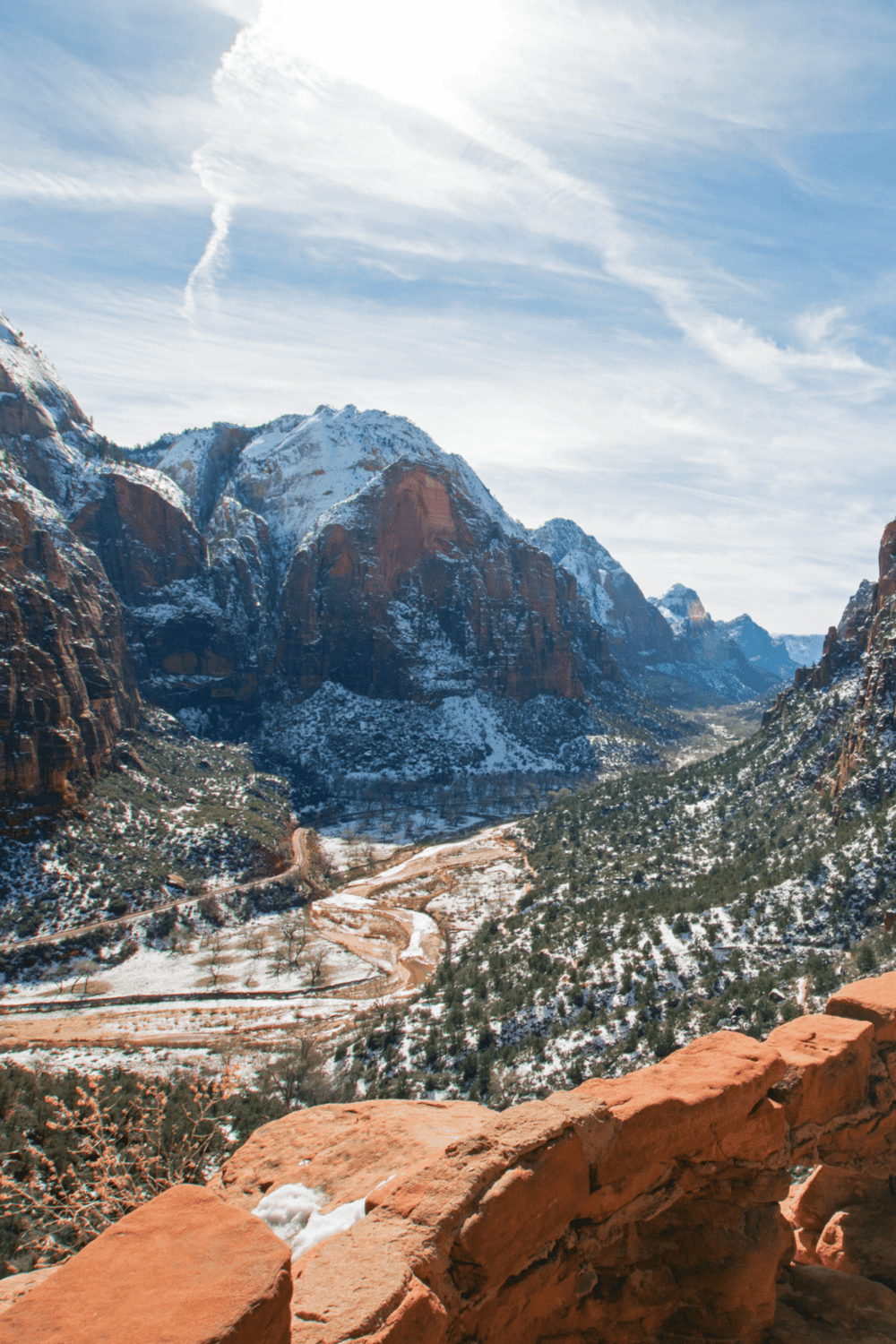 High mountain canyon with snow-covered peaks, scenic valley, and winding dirt road in Zion National Park.