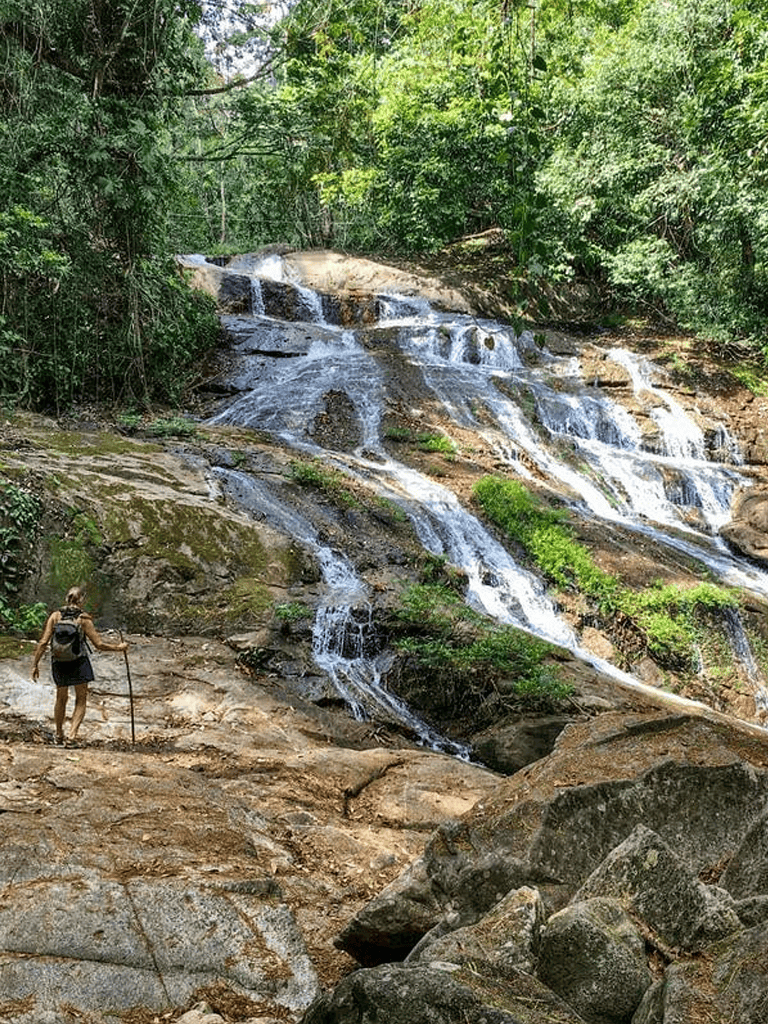 Waterfall in lush forest with hiker, scenic nature trail at Quest for Directions.