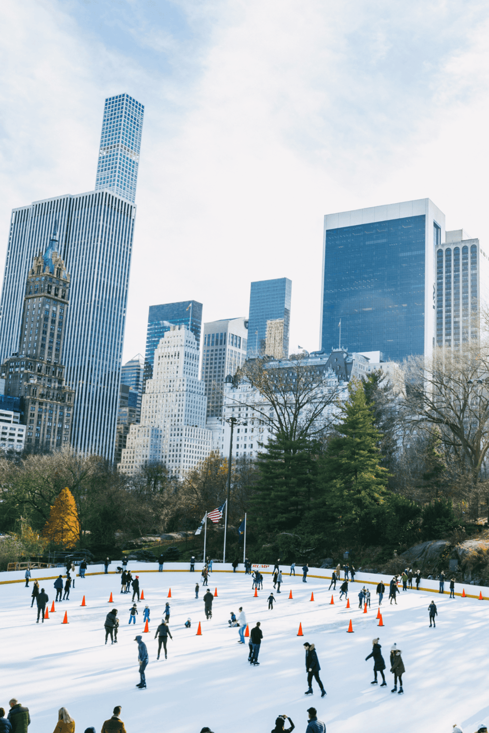 Ice skating rink in Central Park with New York City skyline background.