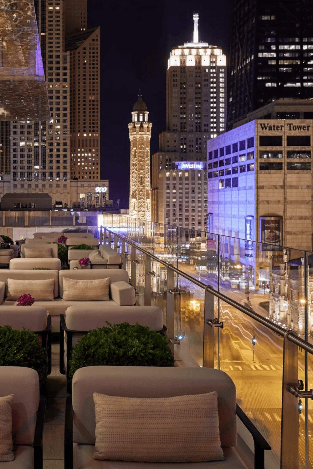 Modern city skyline at night with skyscrapers and a rooftop terrace.