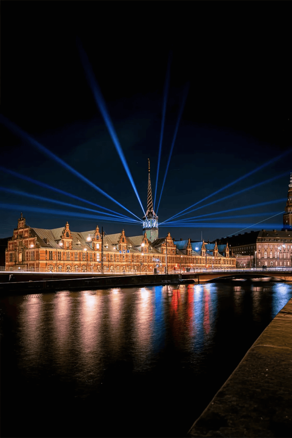 700x100 px, Venice Clock Tower illuminated at night with light beams, reflecting in the water, showcasing Venice tourism and landmarks.