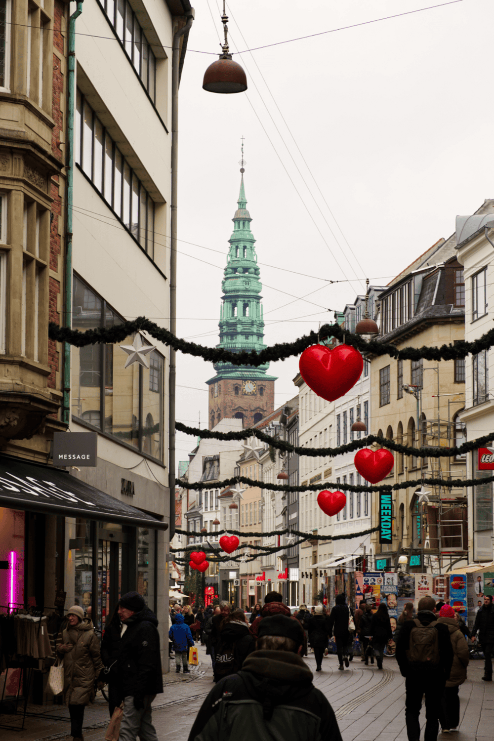 Heart-shaped Christmas decorations hanging in a busy city street.