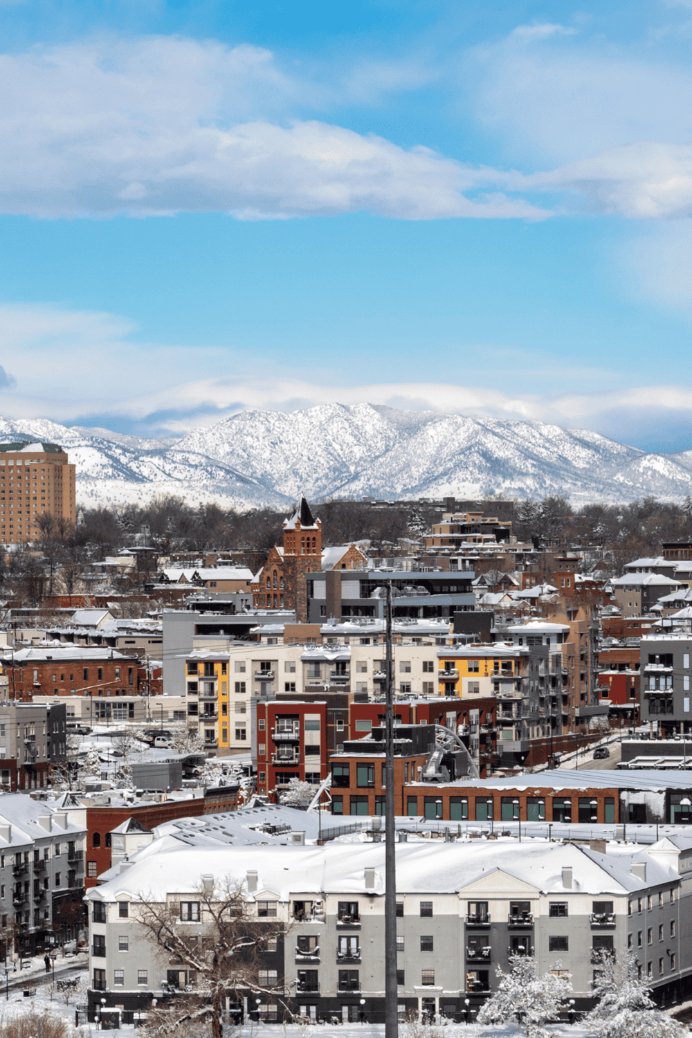 Snowy cityscape with urban buildings and mountain backdrop, showcasing scenic winter views and architectural diversity.