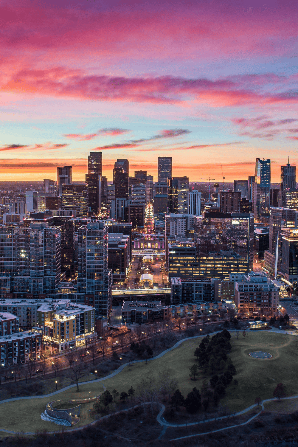 Vibrant city skyline at sunset, showcasing downtown skyscrapers and urban parks.