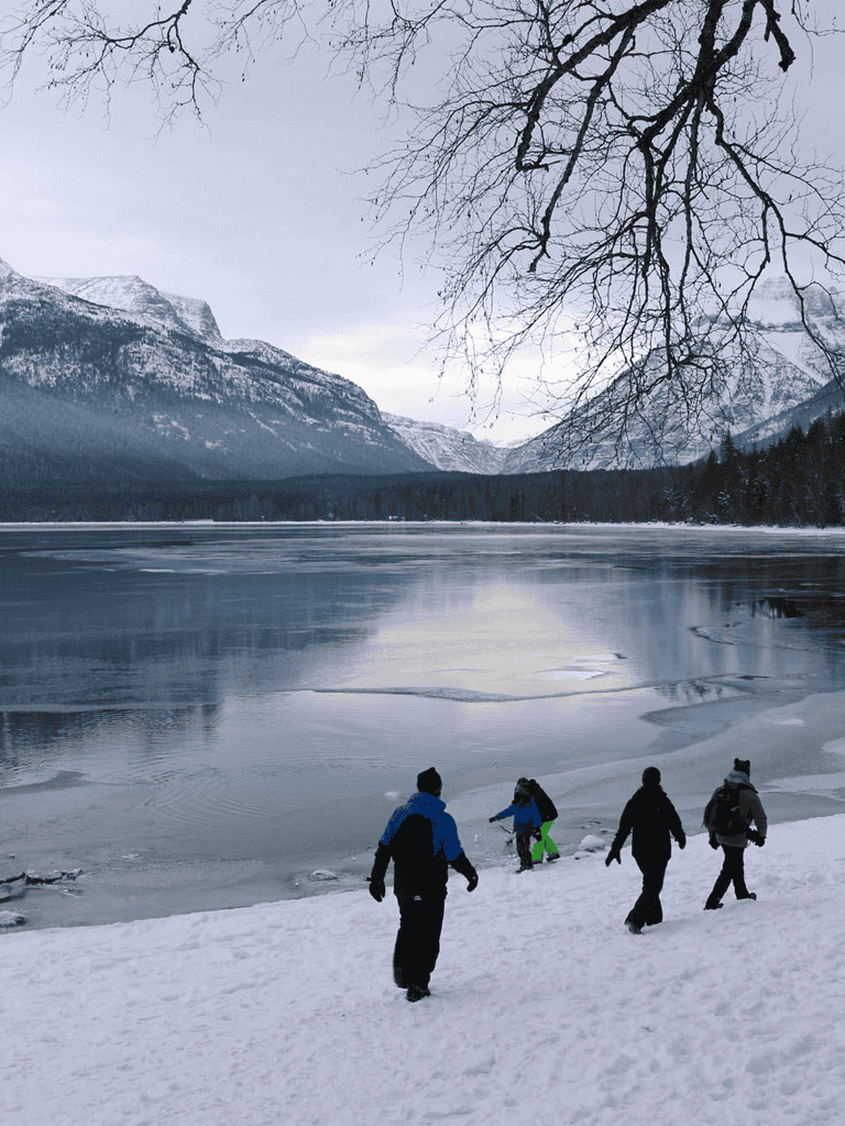 Snowy landscape with mountains and people walking by a frozen lake, winter outdoor adventure, QuestForDirections.