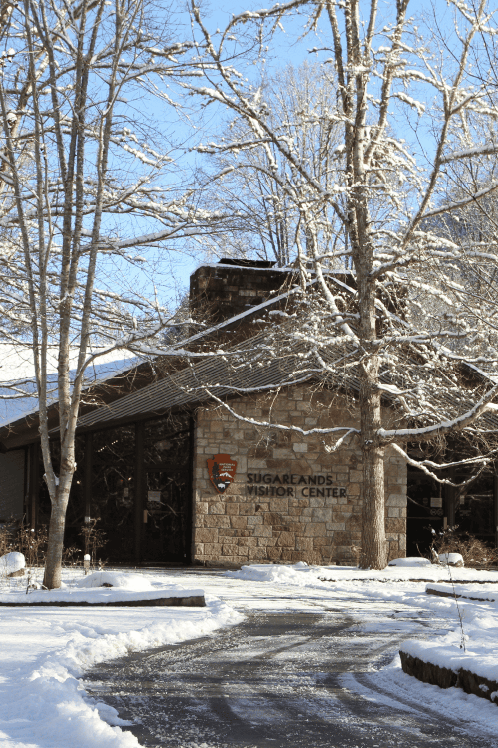 Snow-covered Visitor Center at Sugarlands, surrounded by leafless trees, part of Great Smoky Mountains National Park.