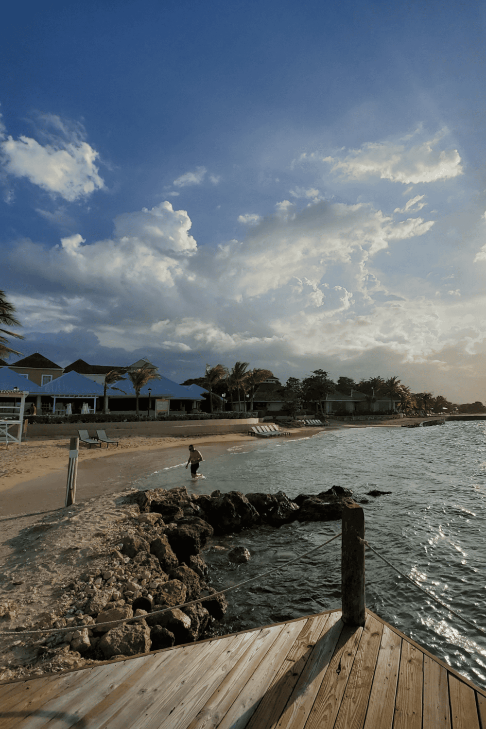 Serene beach scene with clear water, beachfront resorts, and partly cloudy sky, perfect for vacation relaxation.