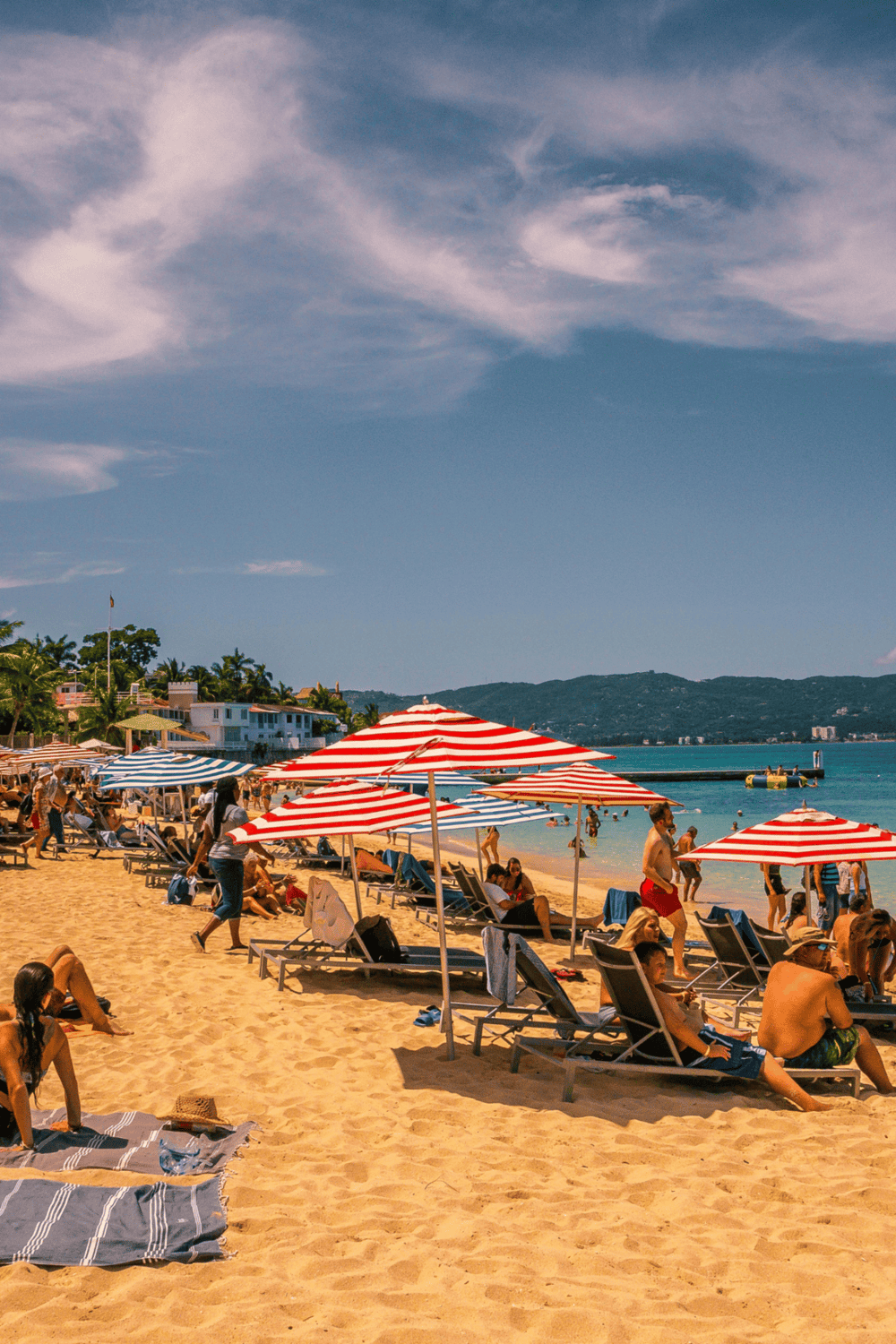 Relaxing beach scene with umbrellas and people enjoying sunny weather, perfect for a summer vacation.