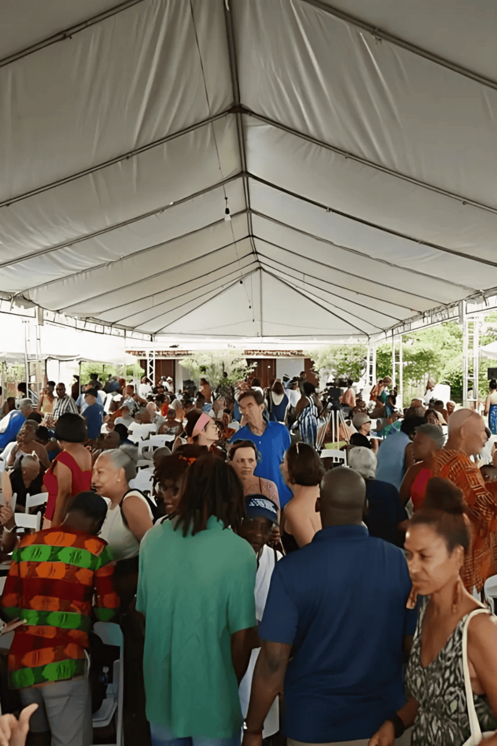 Crowd gathering at an outdoor event under a large tent for community or cultural celebration.