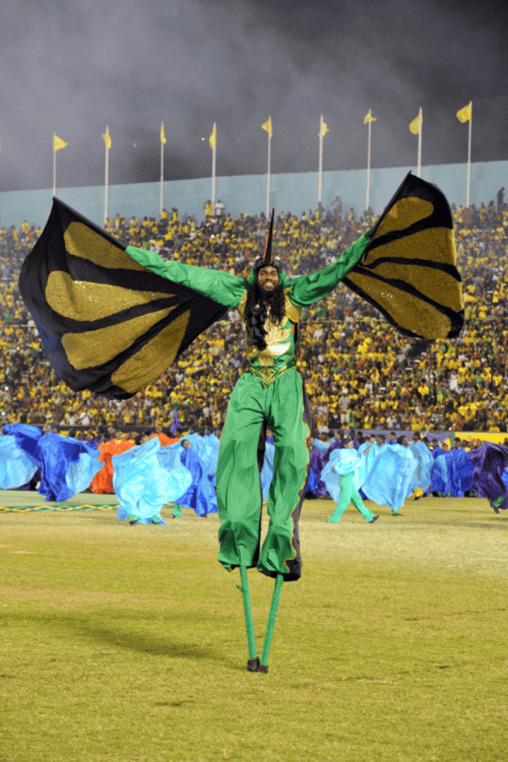 Stilt walker performer at a vibrant stadium event with colorful costumes and enthusiastic crowd.