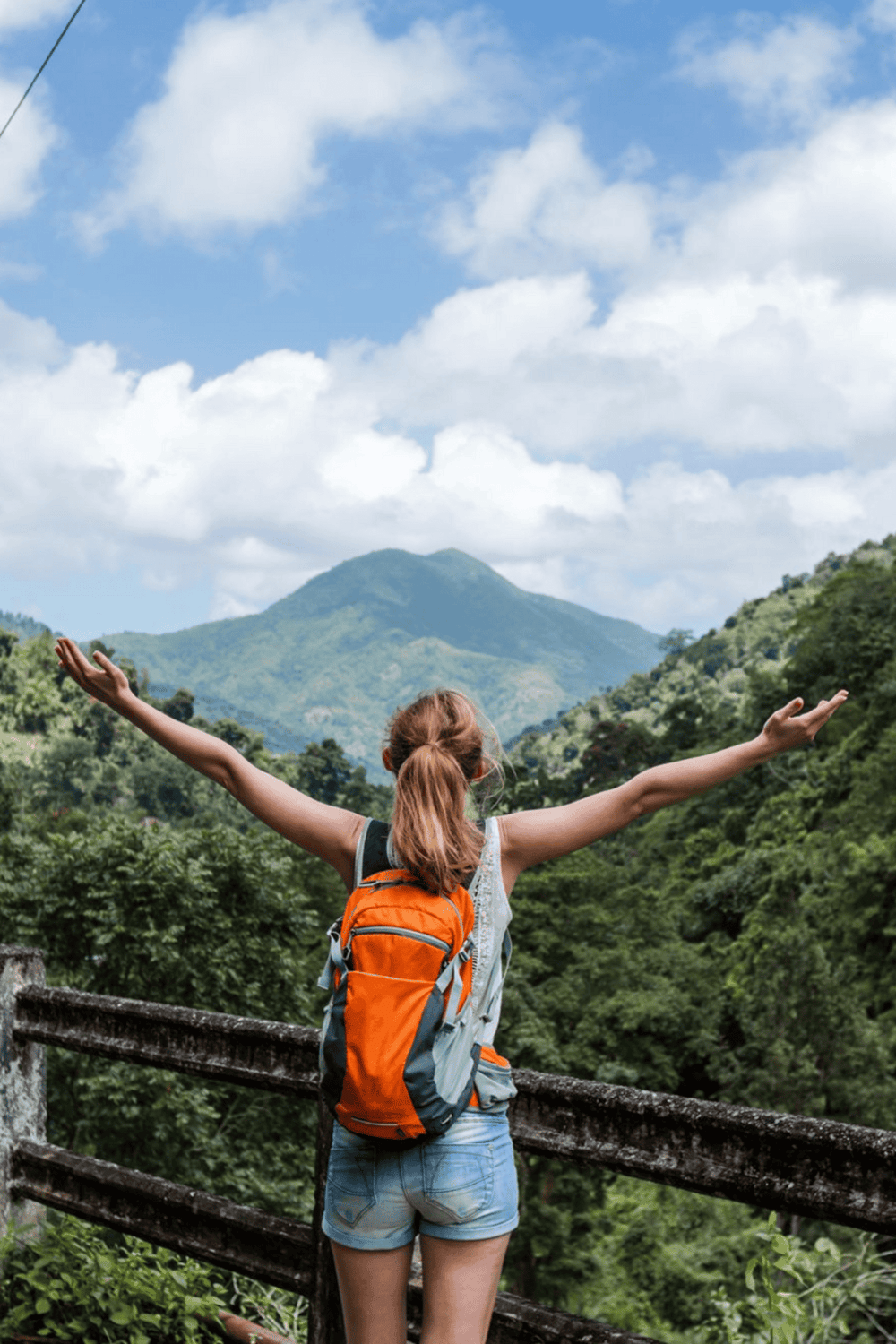 Bright young woman with orange backpack enjoying nature on a scenic mountain hike.