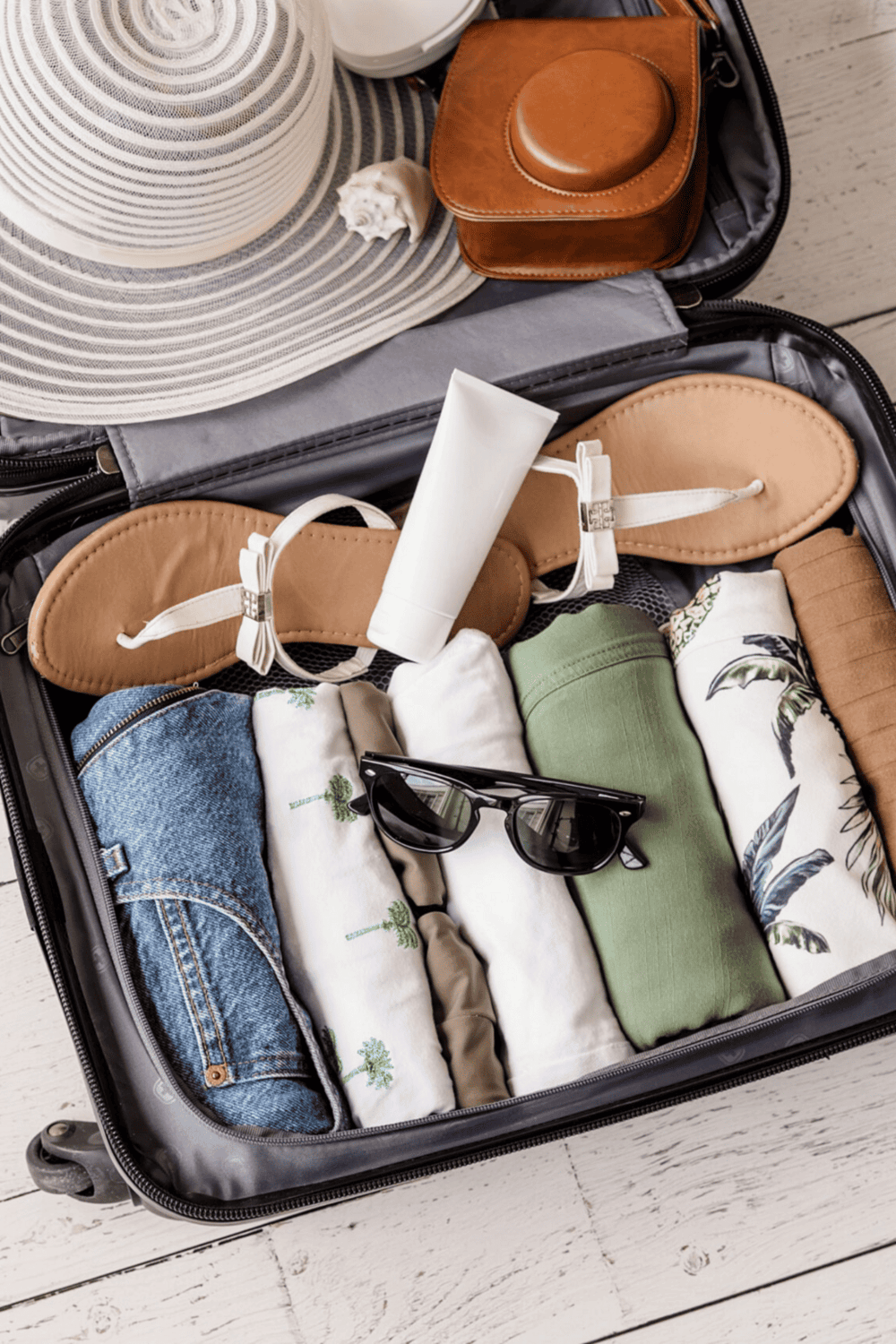 Travel essentials packed in a suitcase for summer vacation with QuestForDirections branding.
