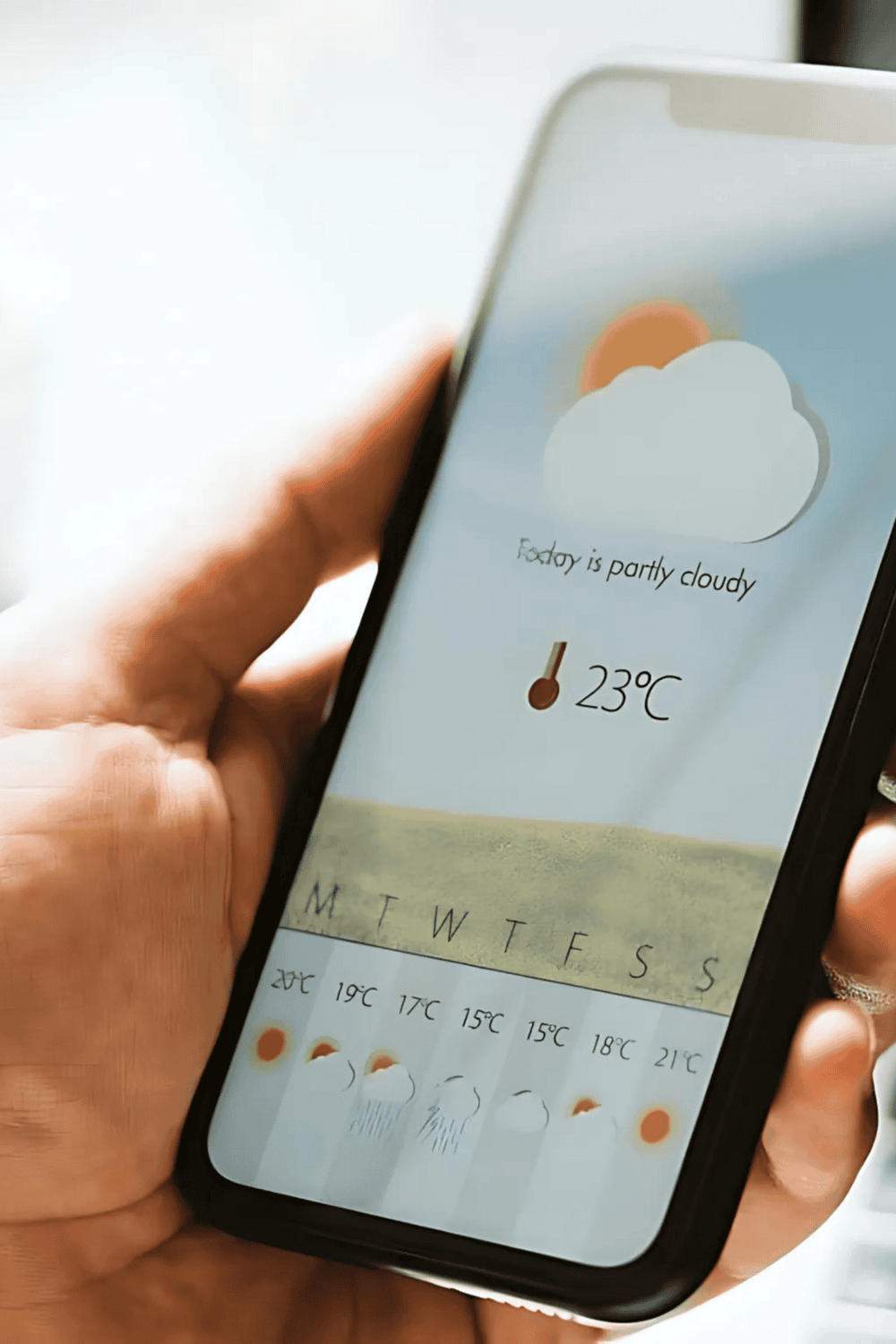 Weather app showing partly cloudy weather and 23°C temperature on smartphone.