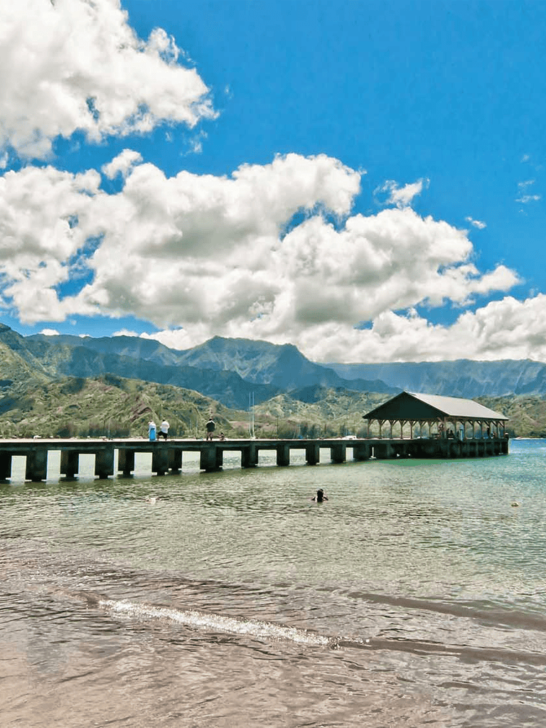 Tranquil lake with mountain backdrop and pier with shelter, scenic outdoor location for relaxation and nature.