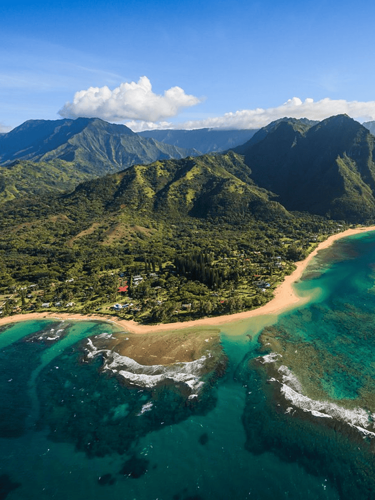 Vibrant Hawaiian coastal landscape with lush green mountains and turquoise ocean waters.