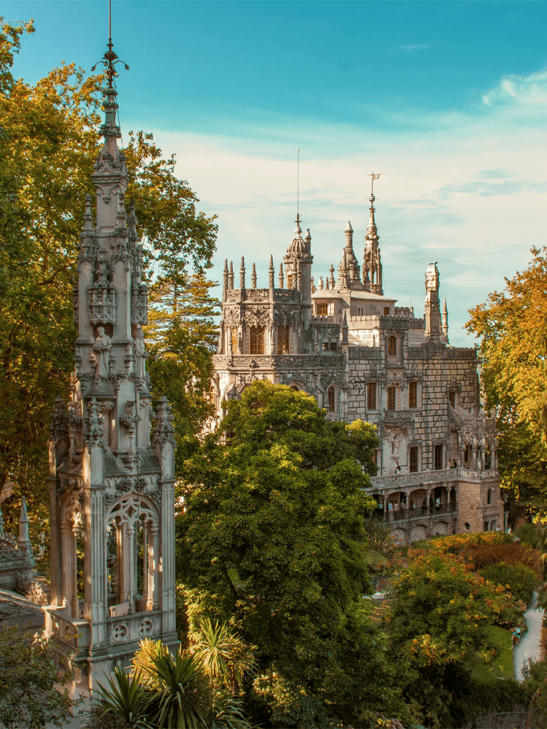 Majestic castle surrounded by lush greenery with detailed gothic architecture, under a vibrant daytime sky.