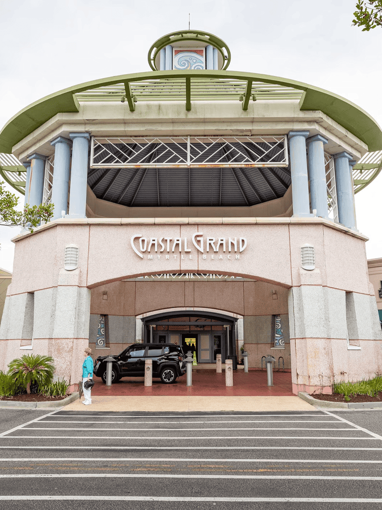 Bright, modern Coastal Grand Myrtle Beach shopping mall entrance with parking and greenery.
