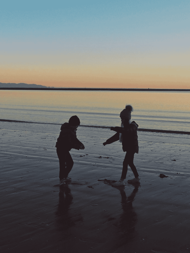 Kids playing at sunset on the beach, exploring and enjoying nature.