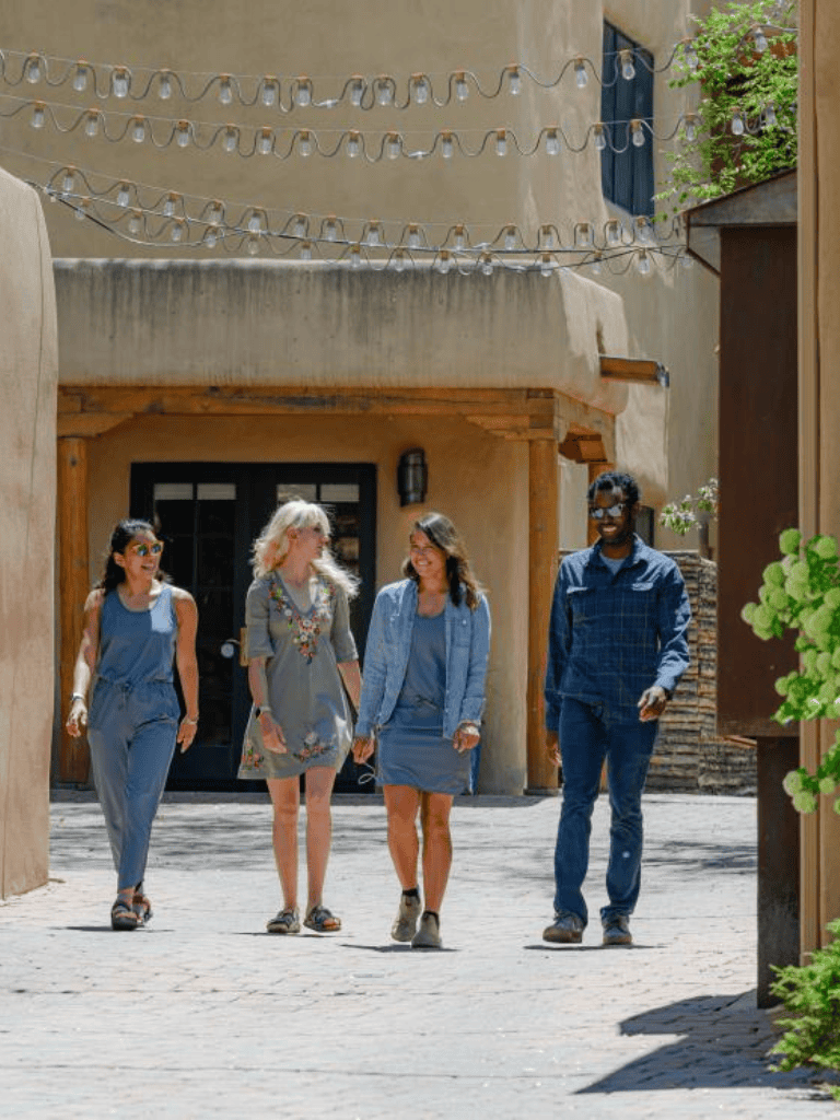 Relaxed diverse group of friends walking in a charming outdoor courtyard, enjoying a sunny day.