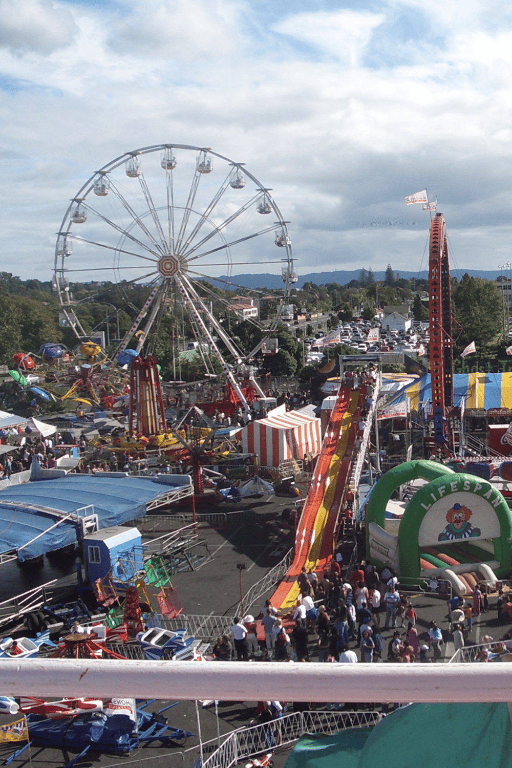 Modern amusement park rides and Ferris wheel at a lively fairground.