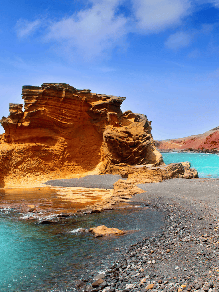 Stunning coastal cliffs with vibrant orange rock formations and turquoise waters under a blue sky.