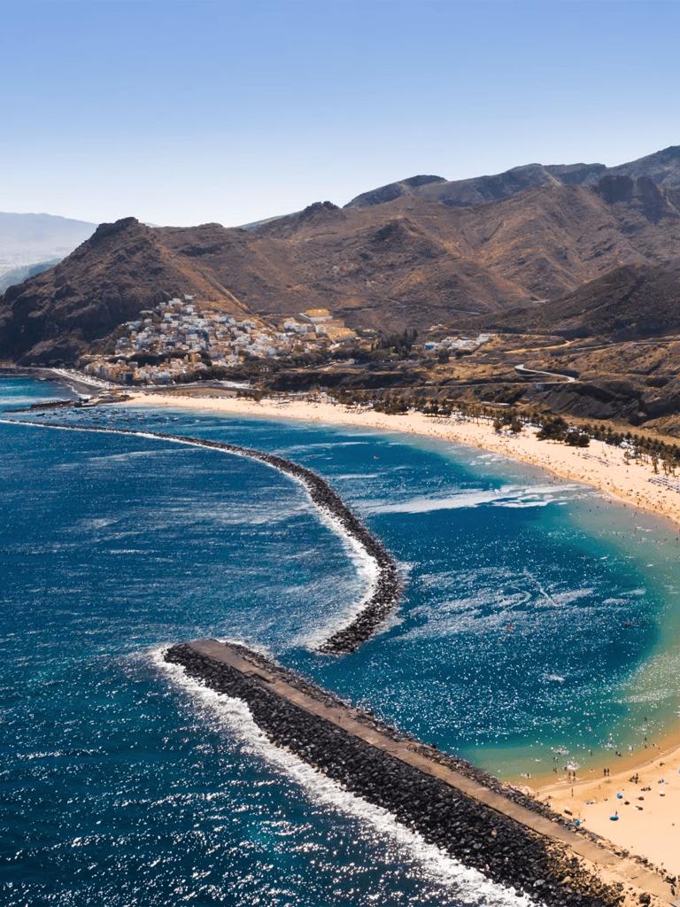 Stunning coastal view of Hawaii with mountains, turquoise waters, and a sandy beach.