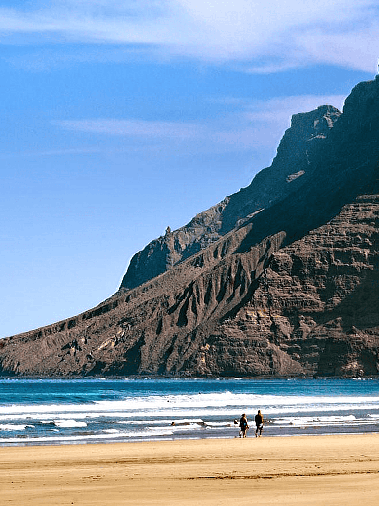 Breathtaking coastal mountain view with sandy beach and visitors enjoying the scenery.