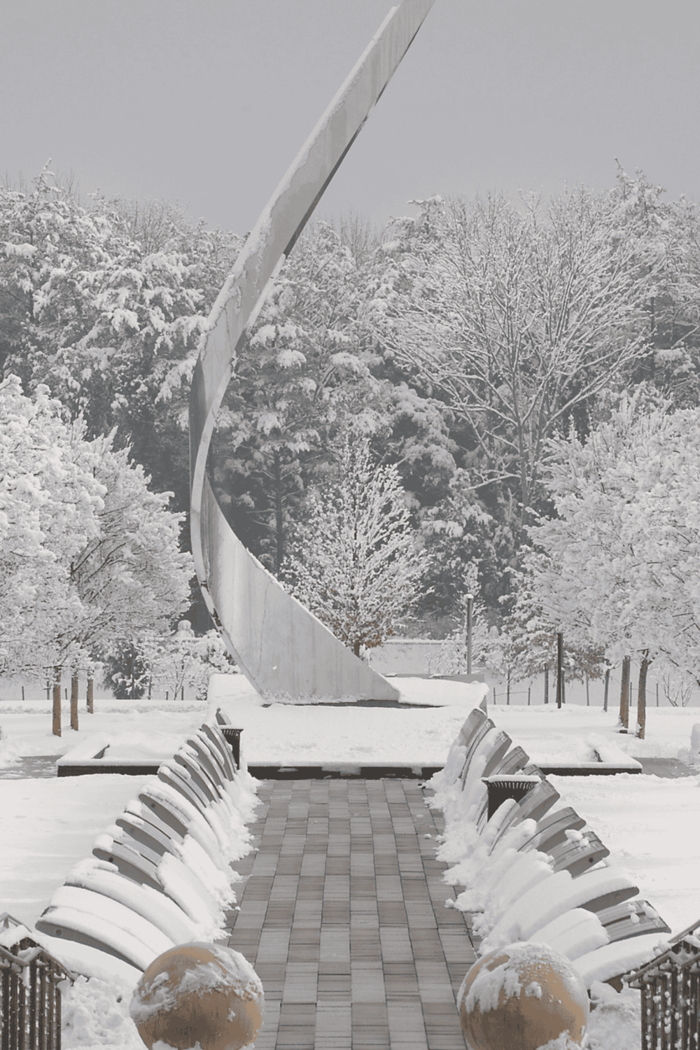 Snow-covered park with modern sculpture and benches, winter scene in Nashville Tennessee.