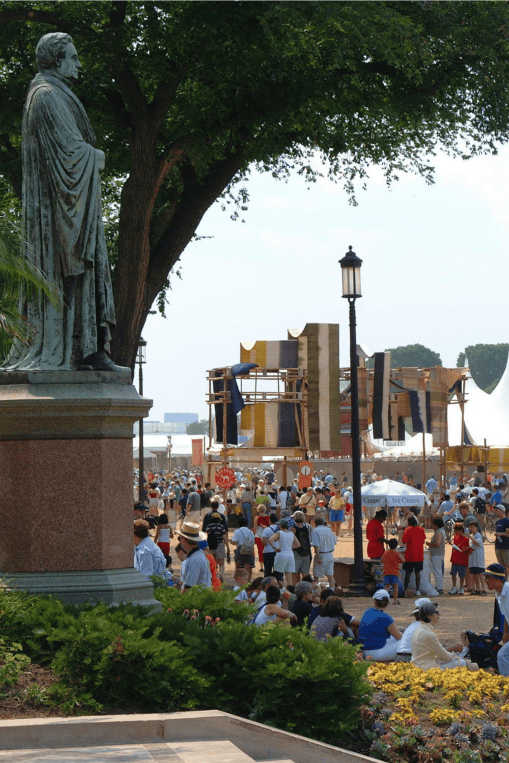 Statue of Abraham Lincoln overlooking a busy outdoor market with tents and shoppers at QuestForDirections.